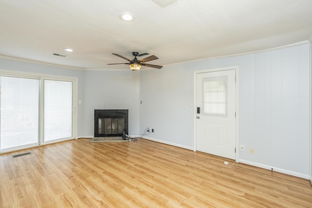 unfurnished living room with a glass covered fireplace, visible vents, plenty of natural light, and light wood-style flooring