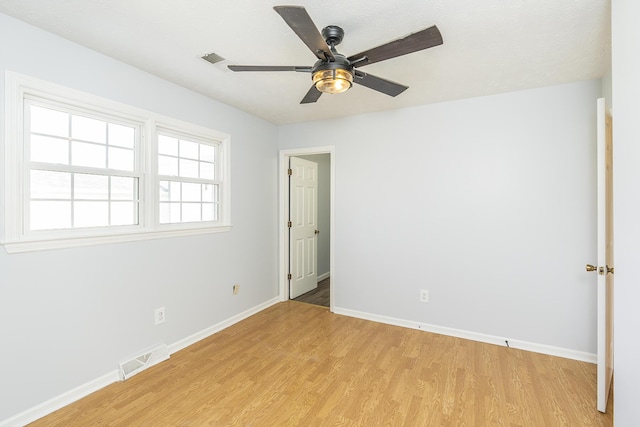 spare room with light wood-type flooring, visible vents, ceiling fan, and baseboards