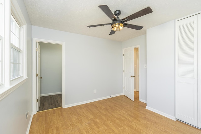 unfurnished bedroom with a textured ceiling, a closet, light wood-style flooring, and baseboards