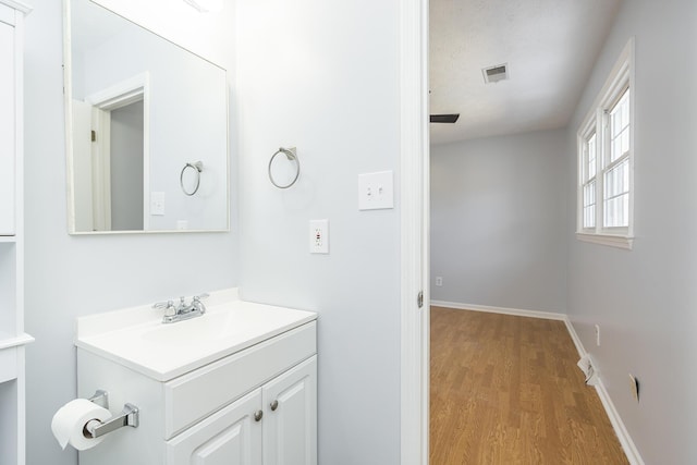 bathroom featuring visible vents, baseboards, wood finished floors, and vanity