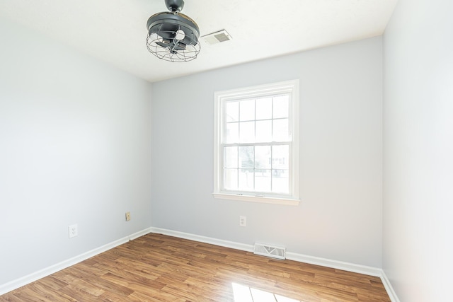 unfurnished room featuring light wood finished floors, visible vents, and baseboards