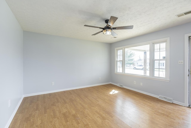 unfurnished room featuring a textured ceiling, light wood-style flooring, visible vents, and baseboards