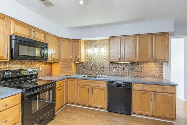 kitchen featuring visible vents, brown cabinetry, dark countertops, black appliances, and a sink