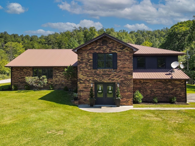 tri-level home with brick siding, a front lawn, metal roof, and french doors