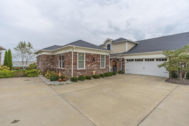 view of front of home featuring a garage, a shingled roof, concrete driveway, and brick siding