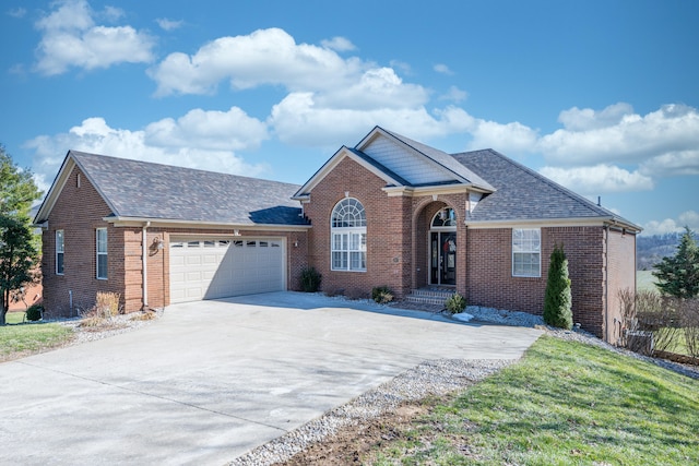 view of front of house featuring driveway, a front yard, a shingled roof, a garage, and brick siding