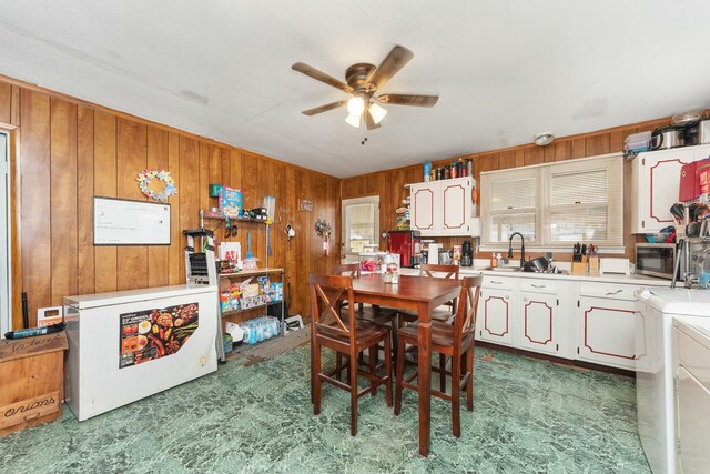 dining space featuring wood walls and a ceiling fan