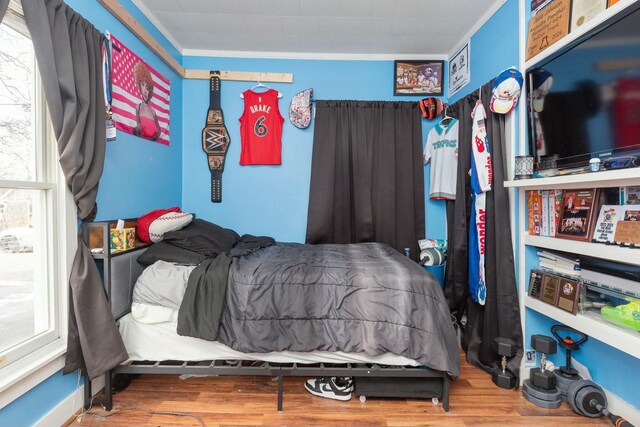 bedroom featuring wood finished floors and crown molding