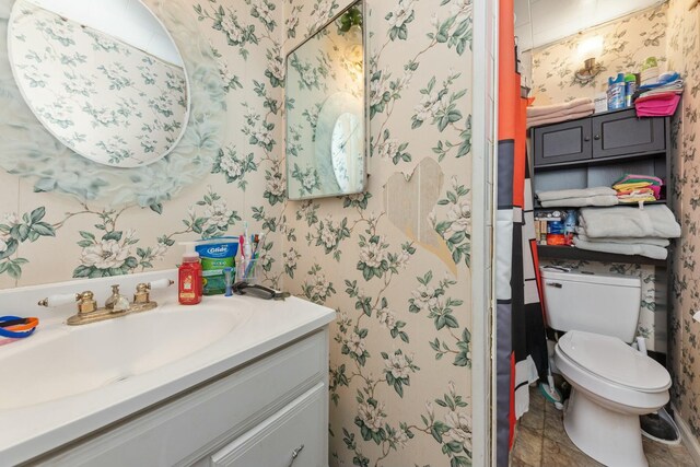 bathroom featuring vanity, toilet, and wallpapered walls