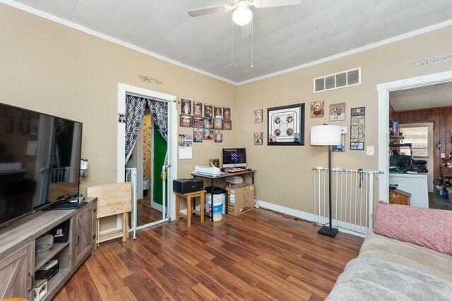 home office featuring dark wood-style floors, crown molding, visible vents, a ceiling fan, and baseboards