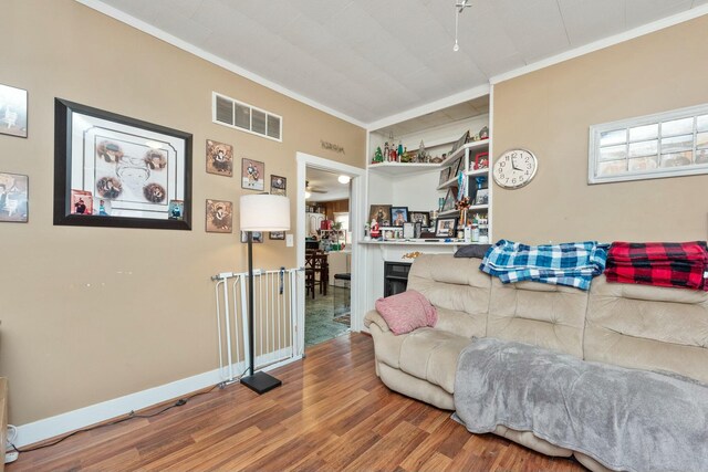 living area with visible vents, crown molding, baseboards, and wood finished floors