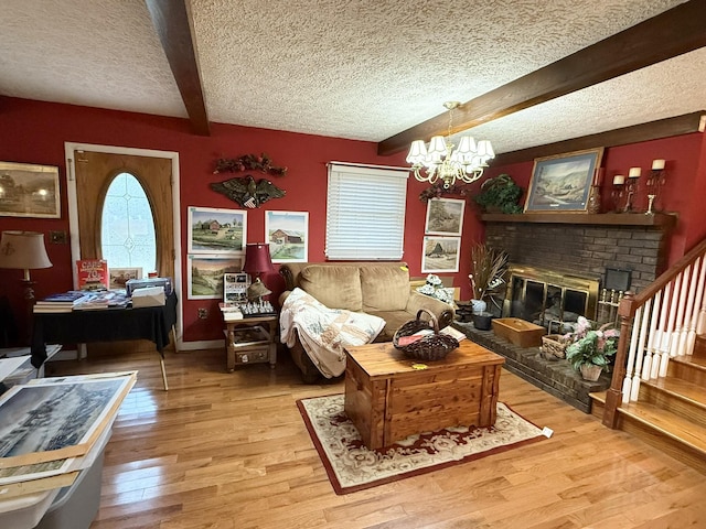 living room with a textured ceiling, light wood-style flooring, a notable chandelier, stairs, and beam ceiling