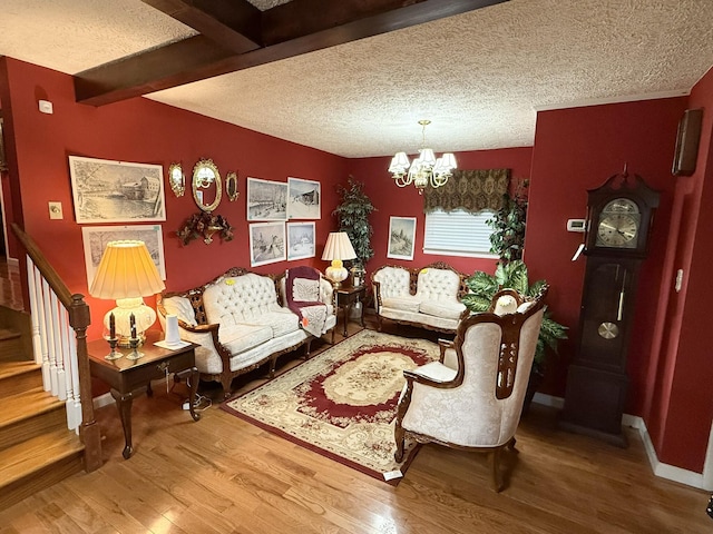 living area featuring a notable chandelier, stairway, a textured ceiling, wood finished floors, and beamed ceiling