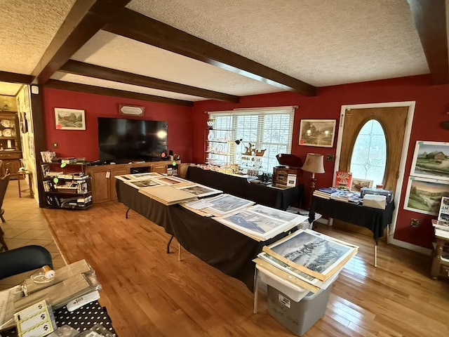 interior space featuring a textured ceiling, light wood finished floors, and beamed ceiling