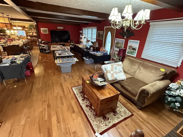 living area featuring a textured ceiling, beamed ceiling, light wood-type flooring, and a notable chandelier