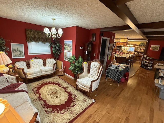 living area with a textured ceiling, beam ceiling, a notable chandelier, and wood finished floors