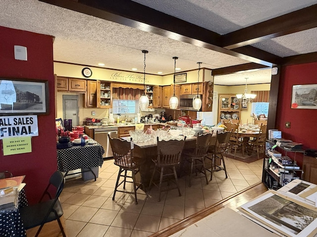 kitchen featuring brown cabinets, pendant lighting, stainless steel appliances, and beam ceiling