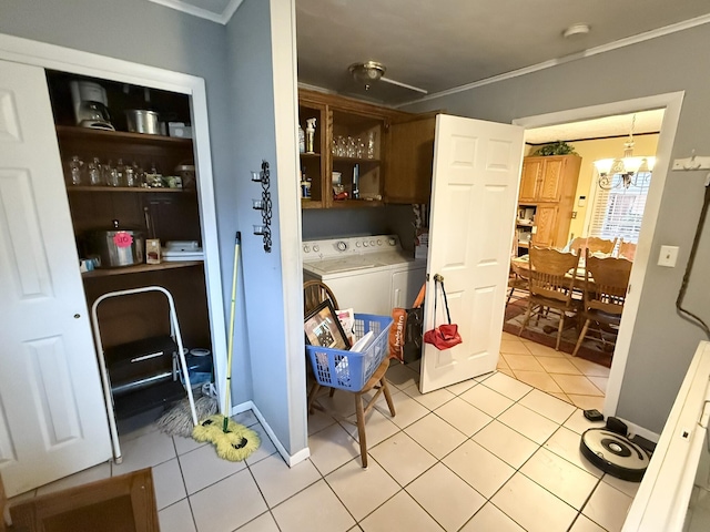 laundry area featuring ornamental molding, washer and dryer, cabinet space, and light tile patterned floors