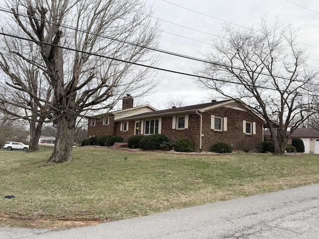 single story home featuring brick siding, a front lawn, and a chimney