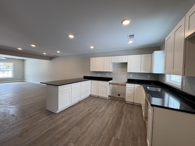 kitchen featuring dark countertops, visible vents, white cabinets, and open floor plan