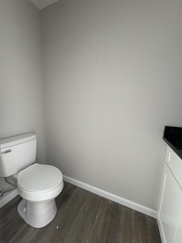 bathroom with toilet, baseboards, wood finished floors, and vanity