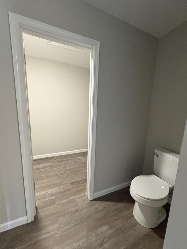 bathroom with toilet, baseboards, and wood finished floors