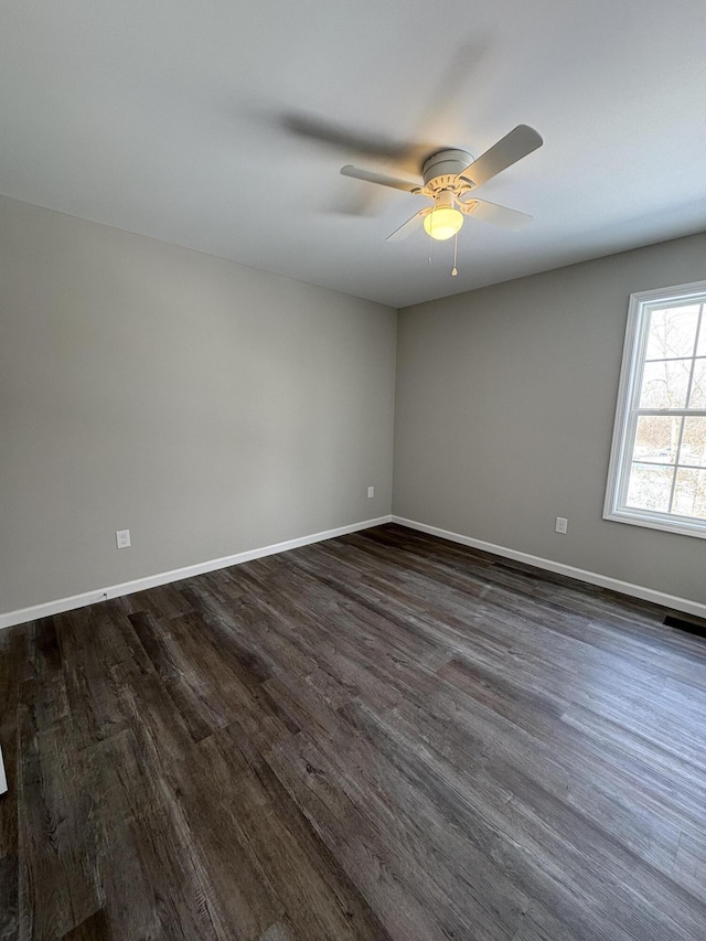 empty room featuring dark wood-type flooring, baseboards, and a ceiling fan