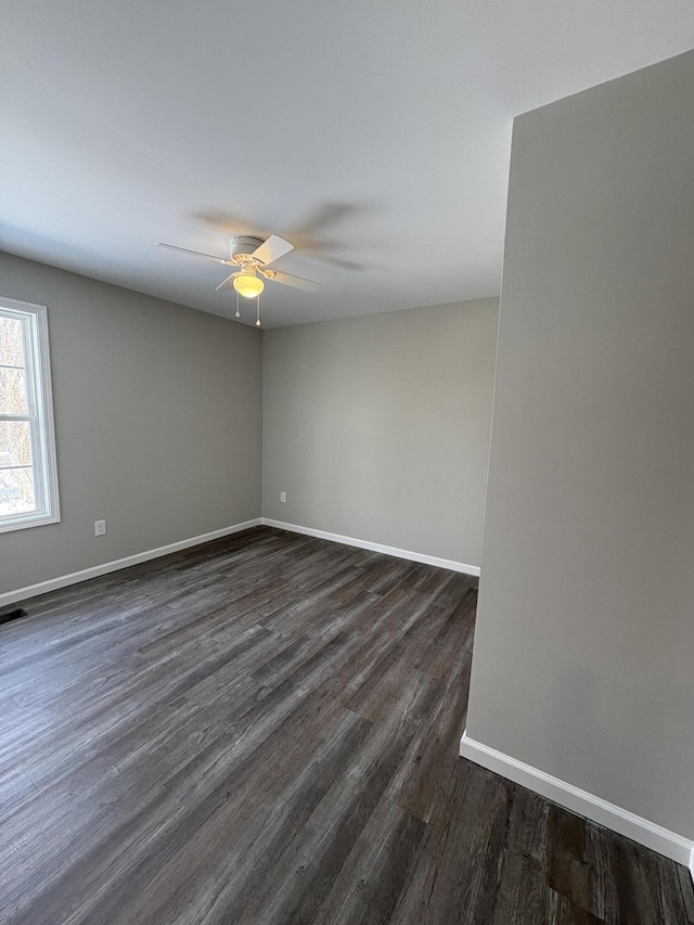 unfurnished room with ceiling fan, dark wood-type flooring, visible vents, and baseboards