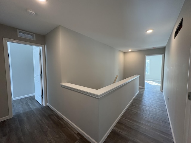 corridor featuring baseboards, visible vents, dark wood-type flooring, and an upstairs landing