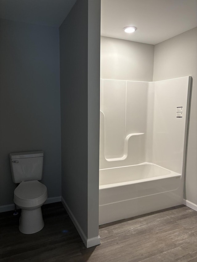 full bath featuring shower / bathtub combination, wood finished floors, toilet, and baseboards