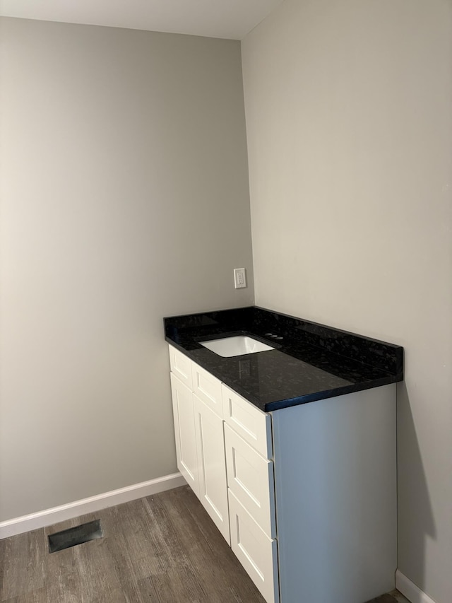 bathroom featuring visible vents, vanity, baseboards, and wood finished floors