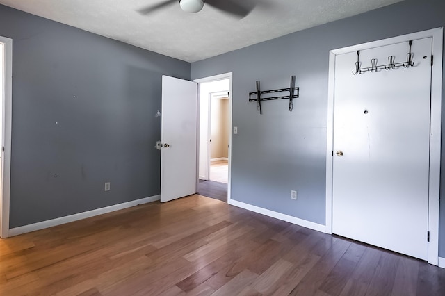 unfurnished bedroom with a textured ceiling, wood finished floors, a ceiling fan, and baseboards