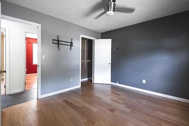 unfurnished bedroom with a textured ceiling, wood finished floors, a ceiling fan, and baseboards