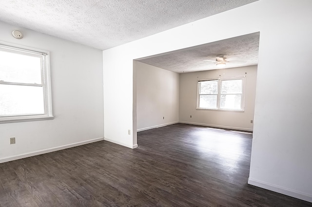 spare room featuring dark wood-style floors, a textured ceiling, baseboards, and a ceiling fan