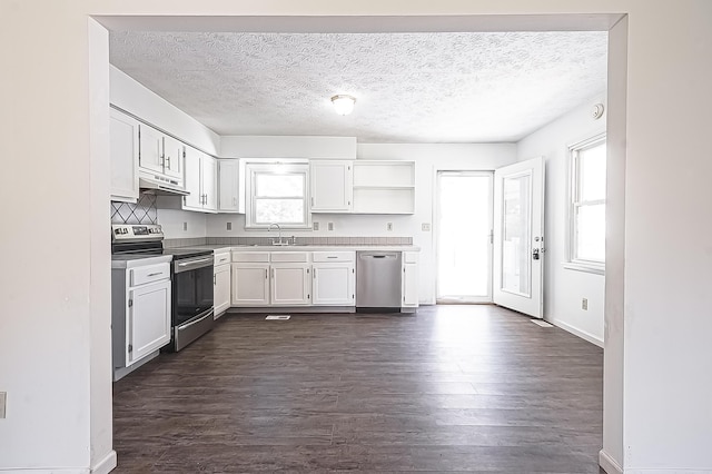 kitchen with under cabinet range hood, a sink, white cabinets, appliances with stainless steel finishes, and dark wood finished floors