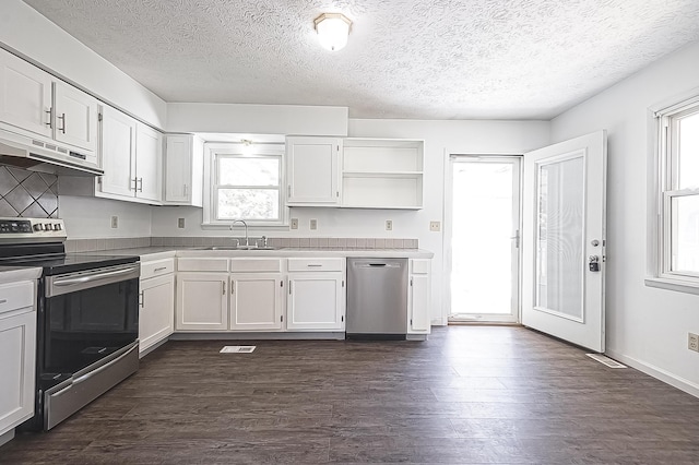 kitchen with stainless steel appliances, dark wood-type flooring, a sink, and white cabinets