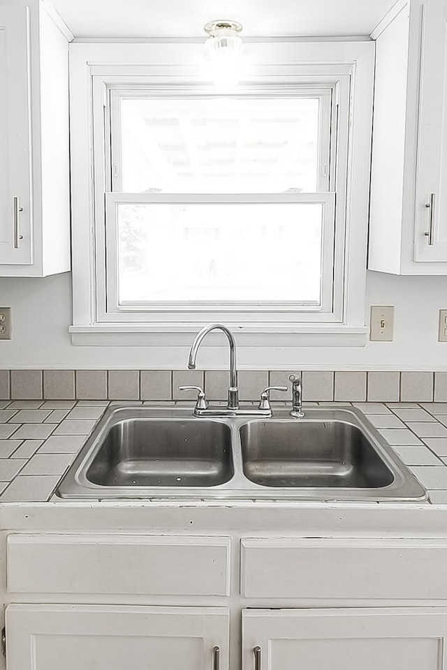 details with white cabinets, a sink, and light countertops