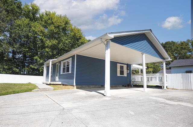 exterior space with a carport, concrete driveway, and fence