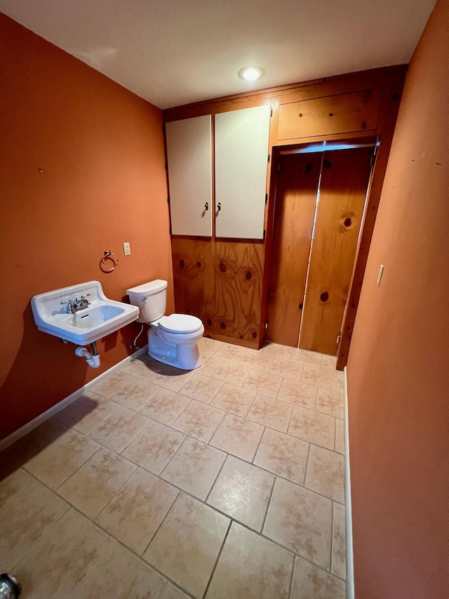 half bathroom featuring a sink, toilet, and tile patterned flooring