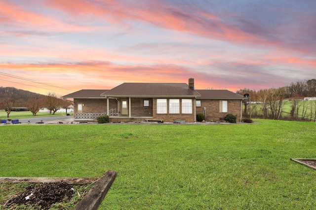 exterior space with a chimney, brick siding, a porch, and a front lawn