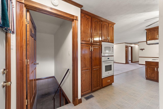 kitchen featuring visible vents, white appliances, baseboards, brown cabinets, and light floors