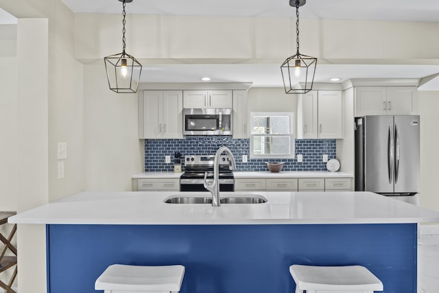 kitchen featuring stainless steel appliances, light countertops, decorative light fixtures, and a kitchen breakfast bar