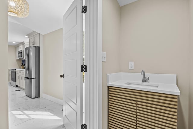 bathroom with marble finish floor, a sink, and baseboards