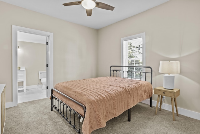 bedroom featuring light carpet, ensuite bathroom, a ceiling fan, and baseboards