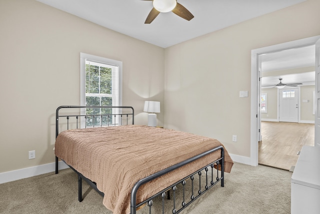 bedroom featuring light carpet, ceiling fan, multiple windows, and baseboards