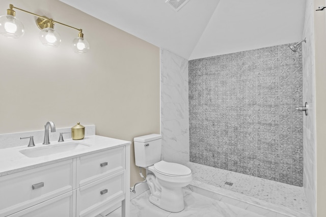 bathroom with toilet, vanity, vaulted ceiling, marble finish floor, and a tile shower