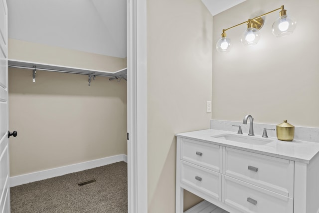 bathroom featuring visible vents, a walk in closet, vanity, and baseboards