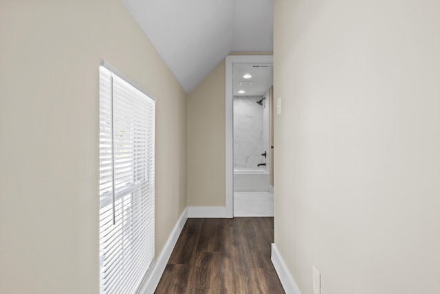 hall with dark wood-style floors, vaulted ceiling, and baseboards