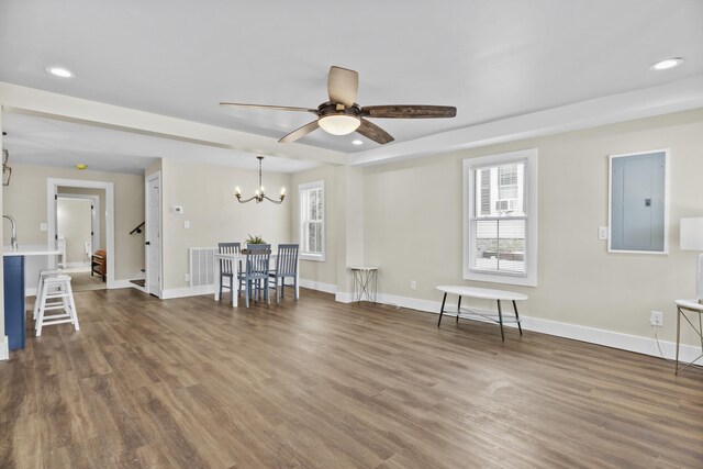 unfurnished living room featuring a wealth of natural light, dark wood-type flooring, electric panel, and baseboards