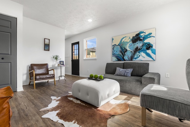 living room featuring a textured ceiling, baseboards, and wood finished floors